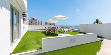 a patio with umbrellas and chairs on a green lawn