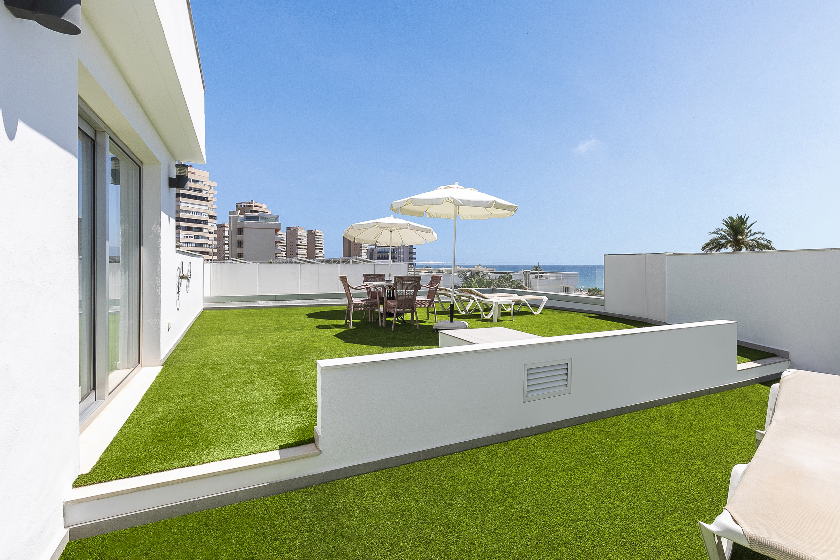a patio with umbrellas and chairs on a green lawn