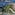 Sunny coastal resort aerial view: beach, blue pools, hotels, ocean.