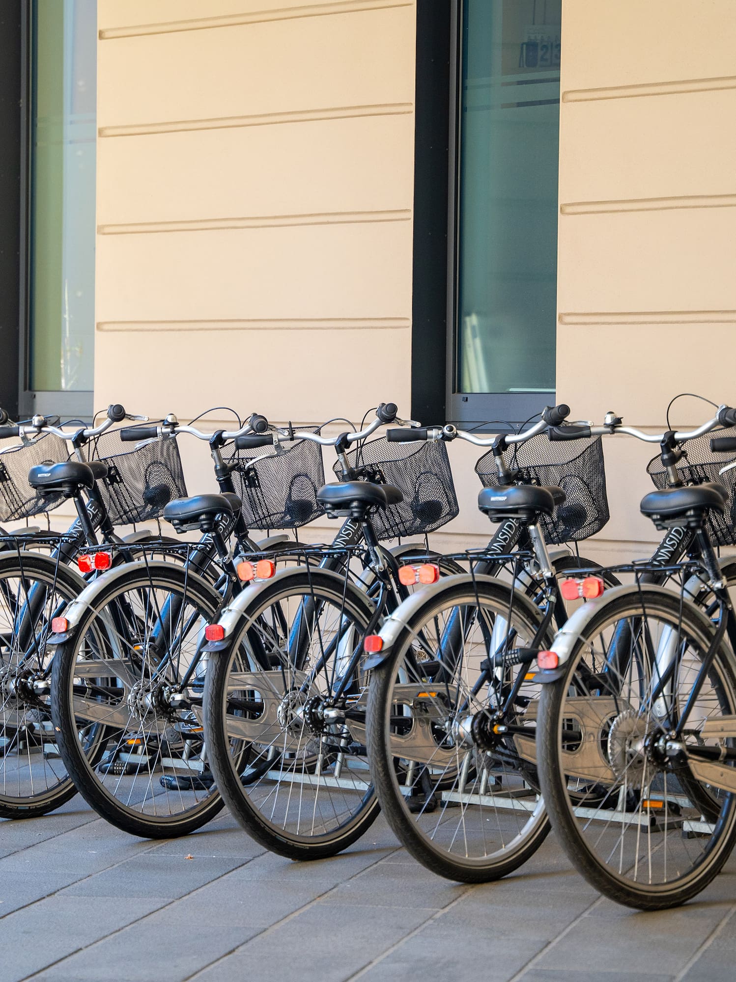 Dark INNSIDE rental bikes with baskets parked in a hotel bike rack.