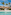 Luxury resort pool with palm trees, thatched roof, and canopy daybed.