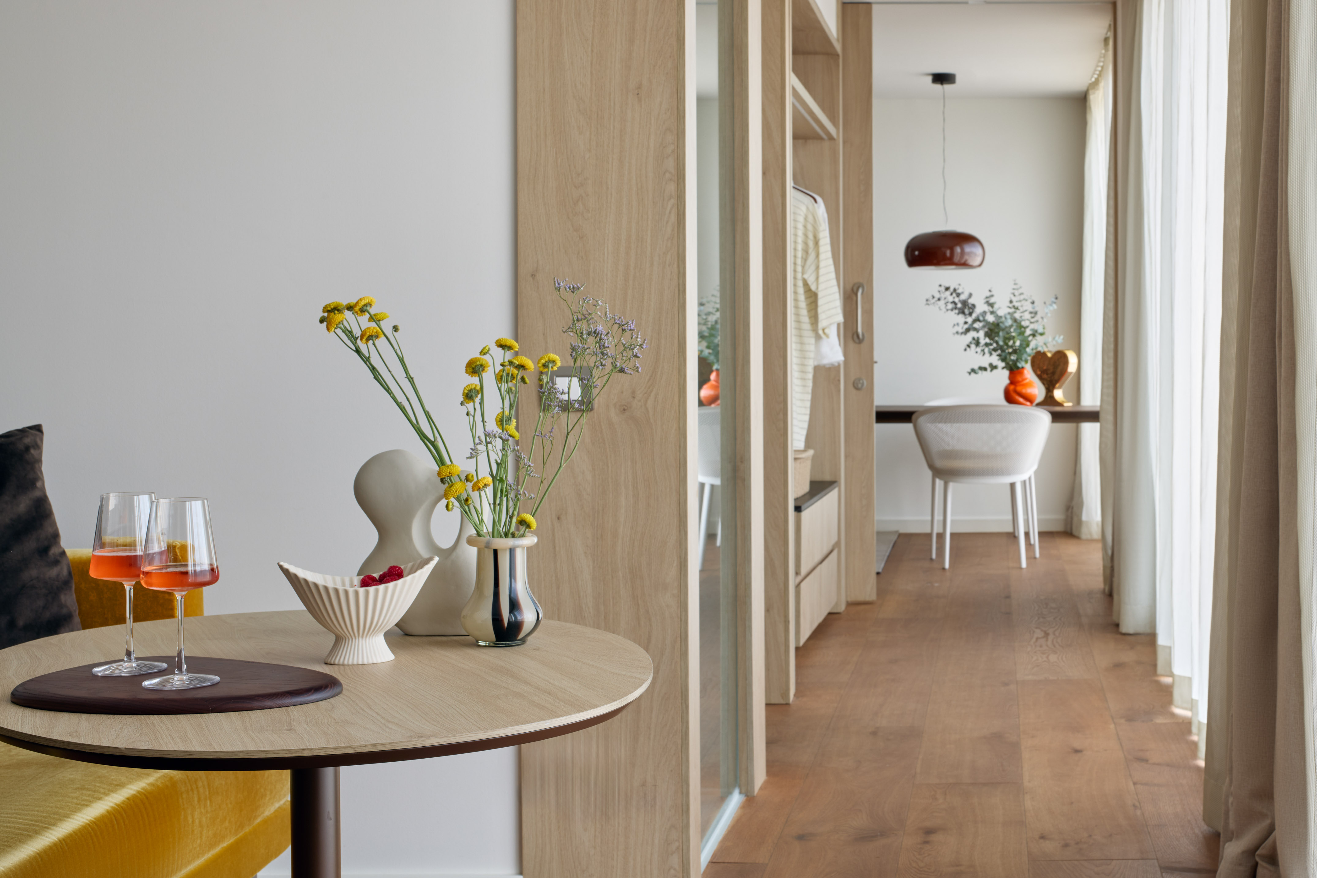 Modern living area with drinks, flowers on table, hardwood floor.