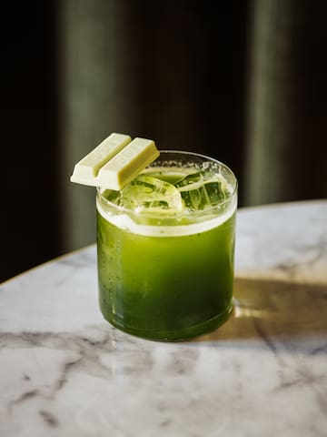 a glass of green liquid with a white bar on top