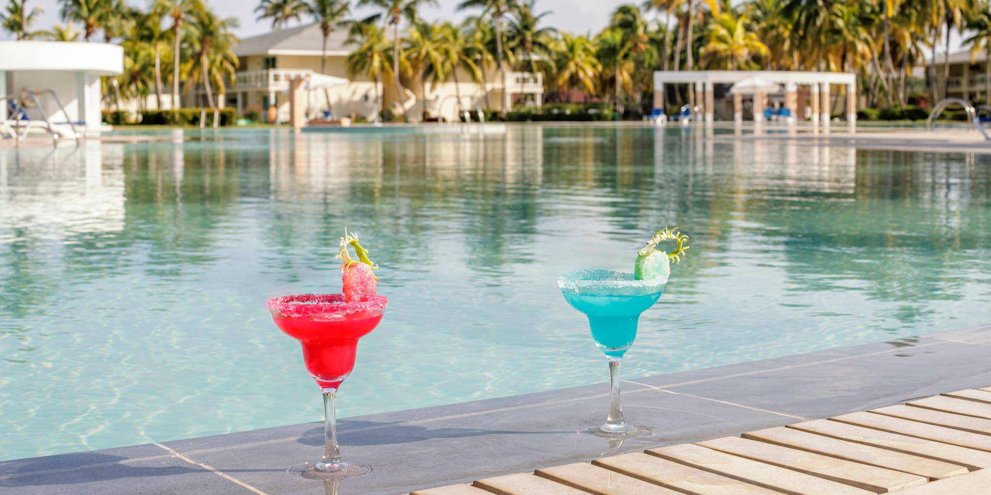 two glasses of drinks by a pool