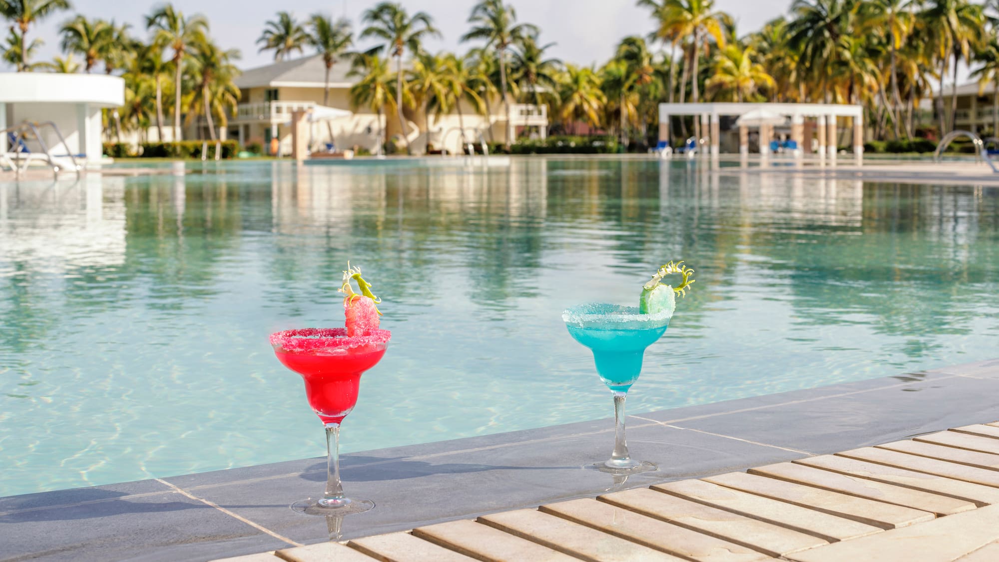 two glasses of drinks by a pool