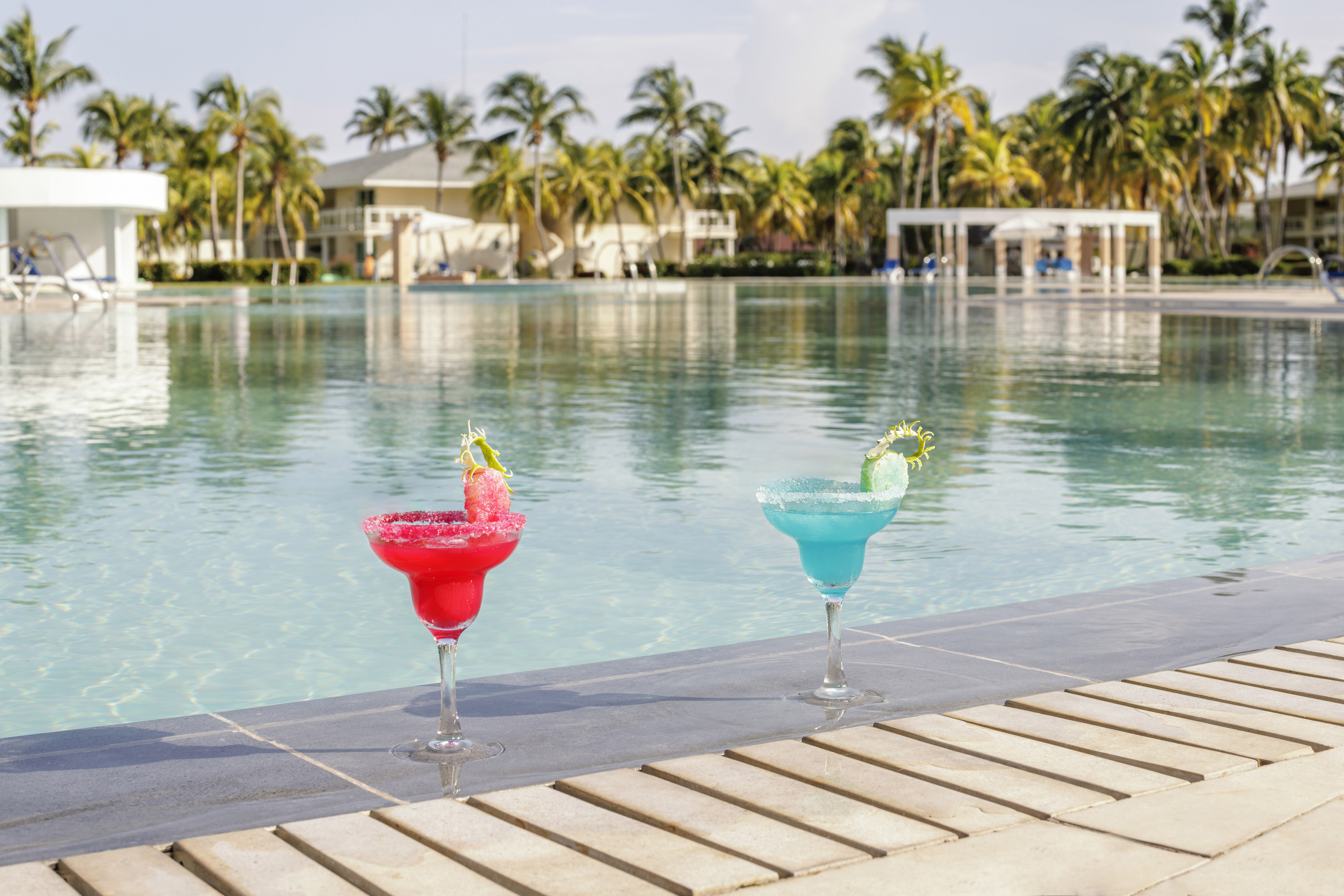 two glasses of drinks by a pool