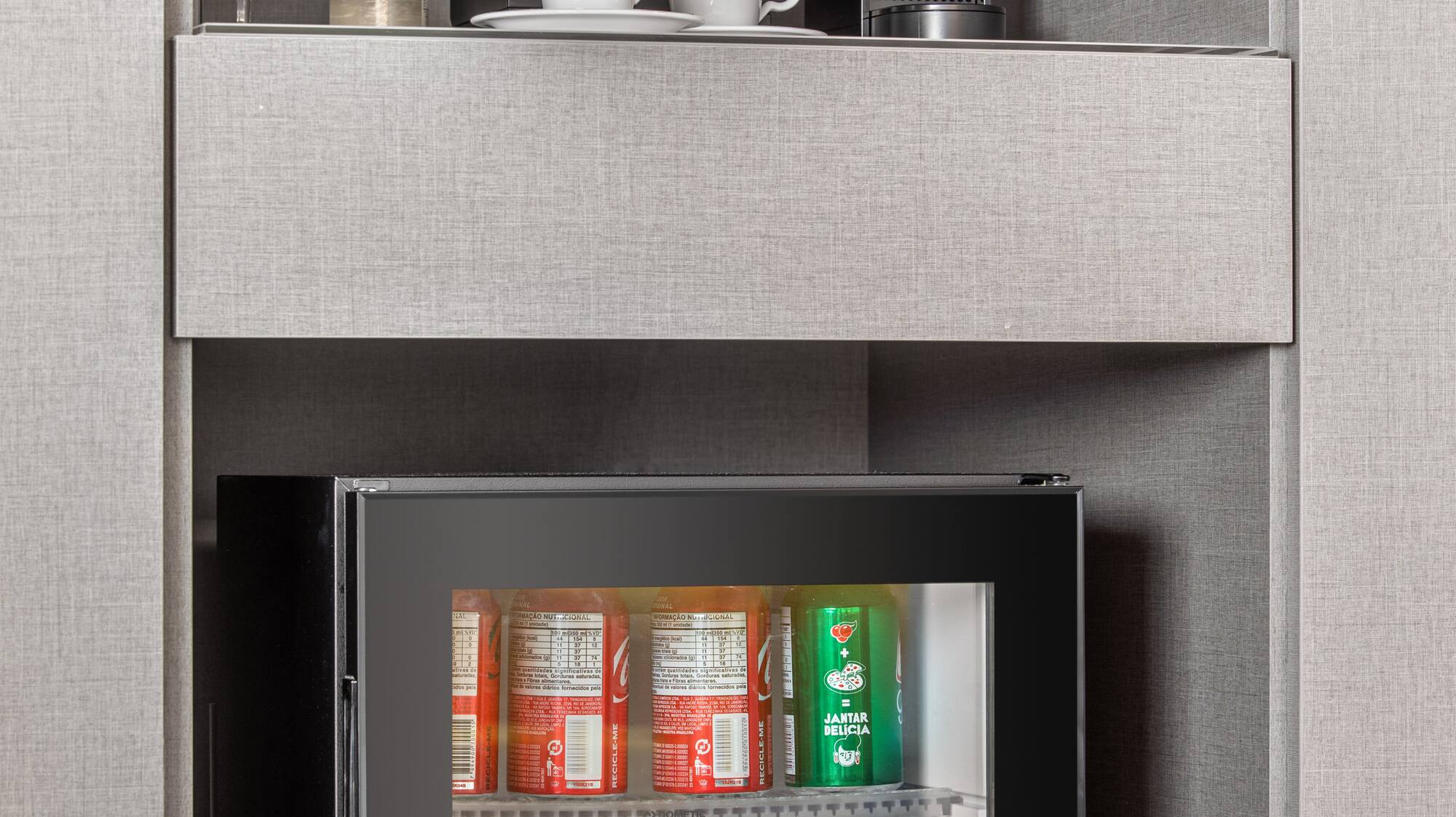 a small refrigerator with drinks and cups on top of it