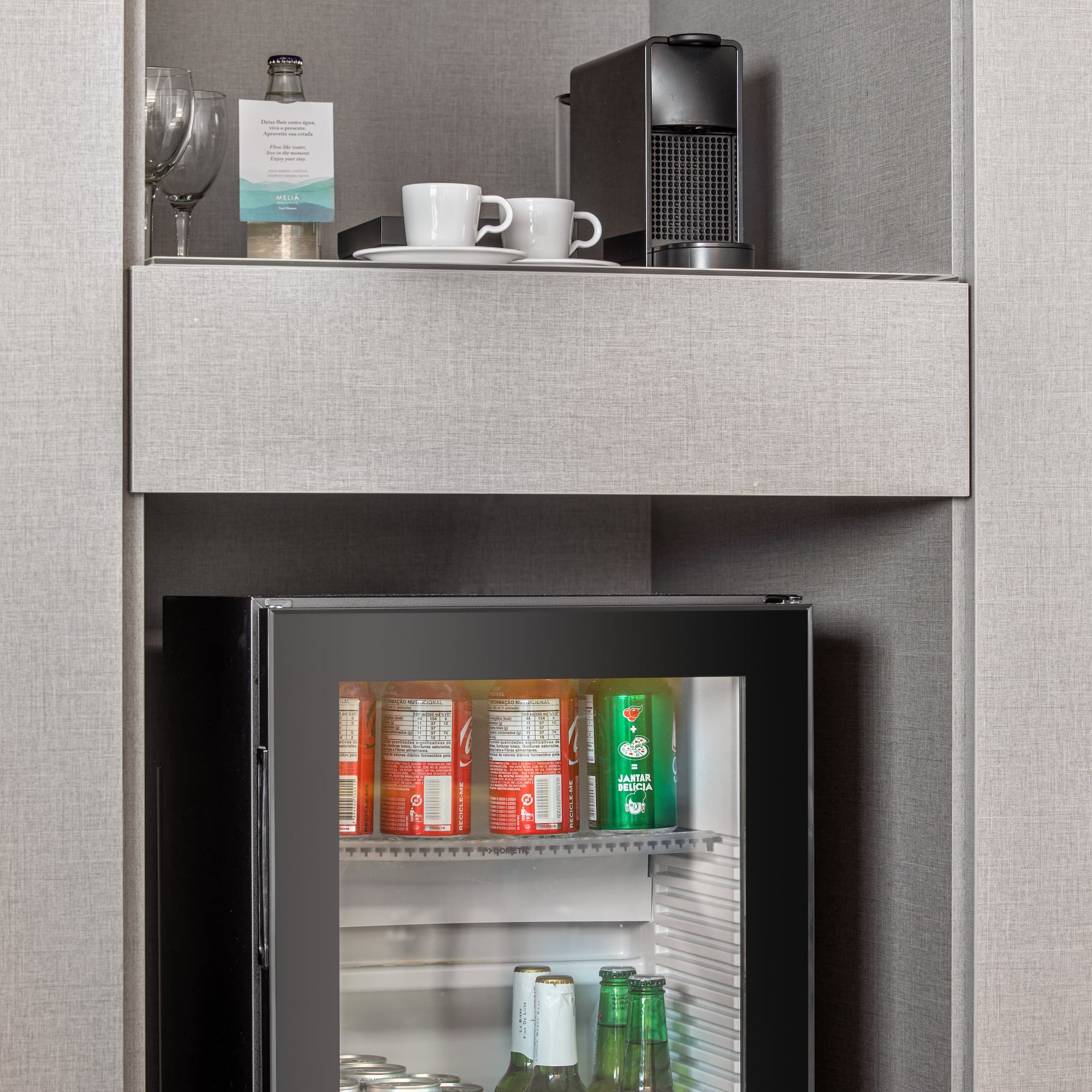 a small refrigerator with drinks and cups on top of it