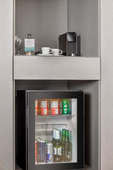a small refrigerator with drinks and cups on top of it