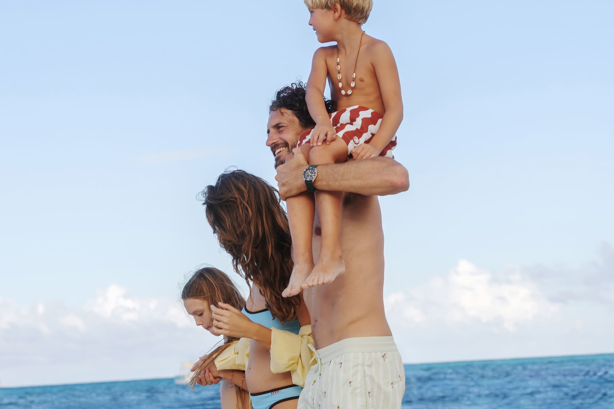 a man holding a child on his shoulders on a beach