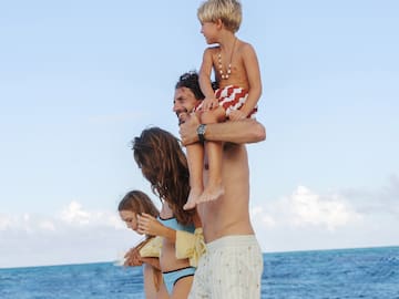 a man holding a child on his shoulders on a beach