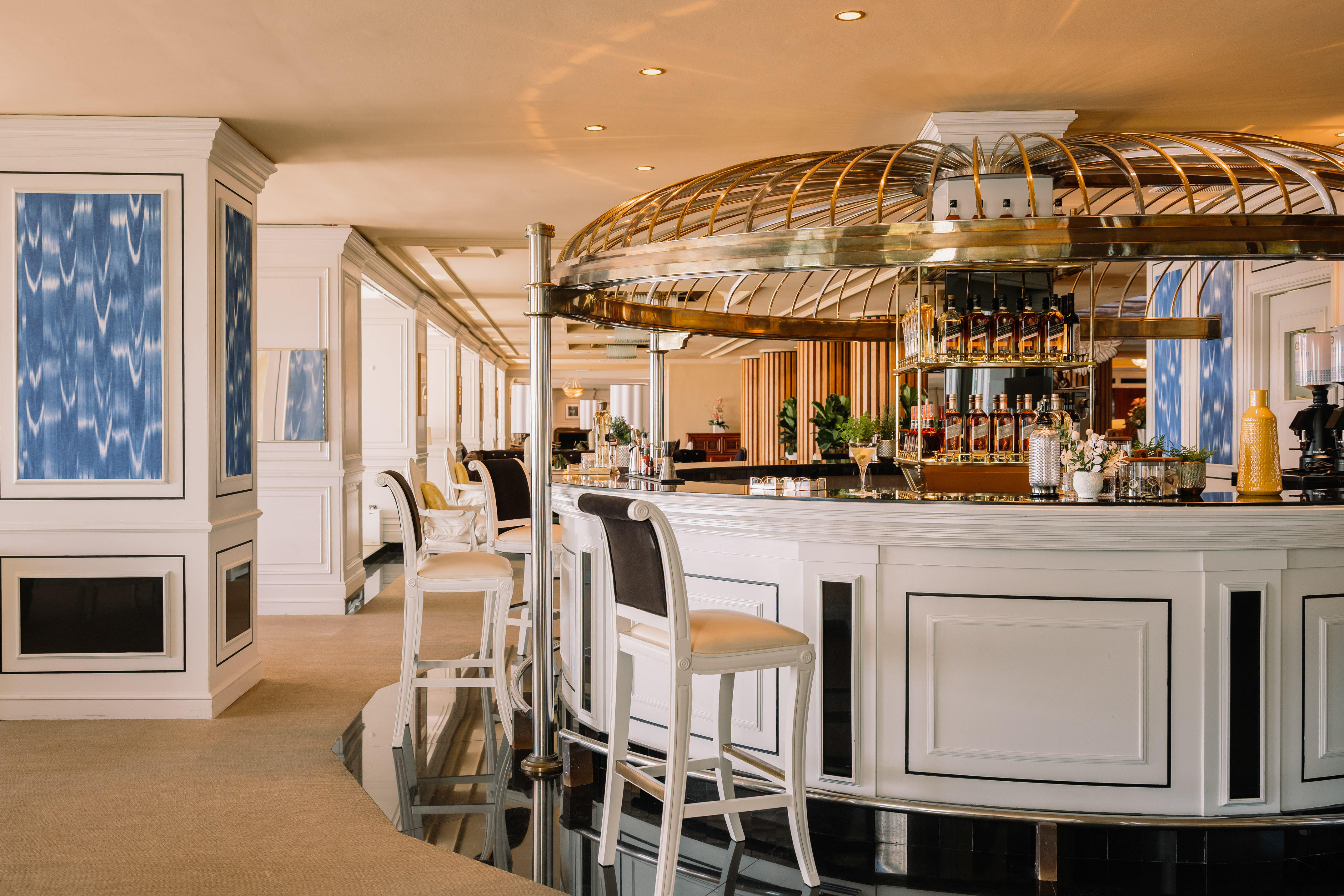 Elegant hotel bar with white counter, golden dome, and liquor display.