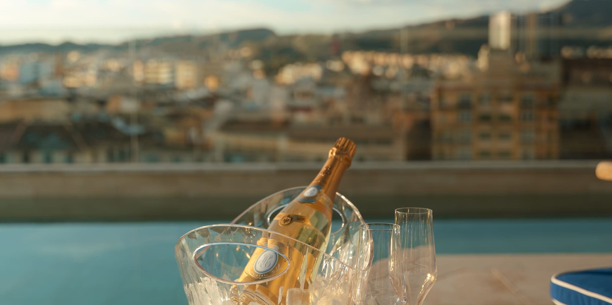 a bottle in a bucket of ice and two glasses on a table