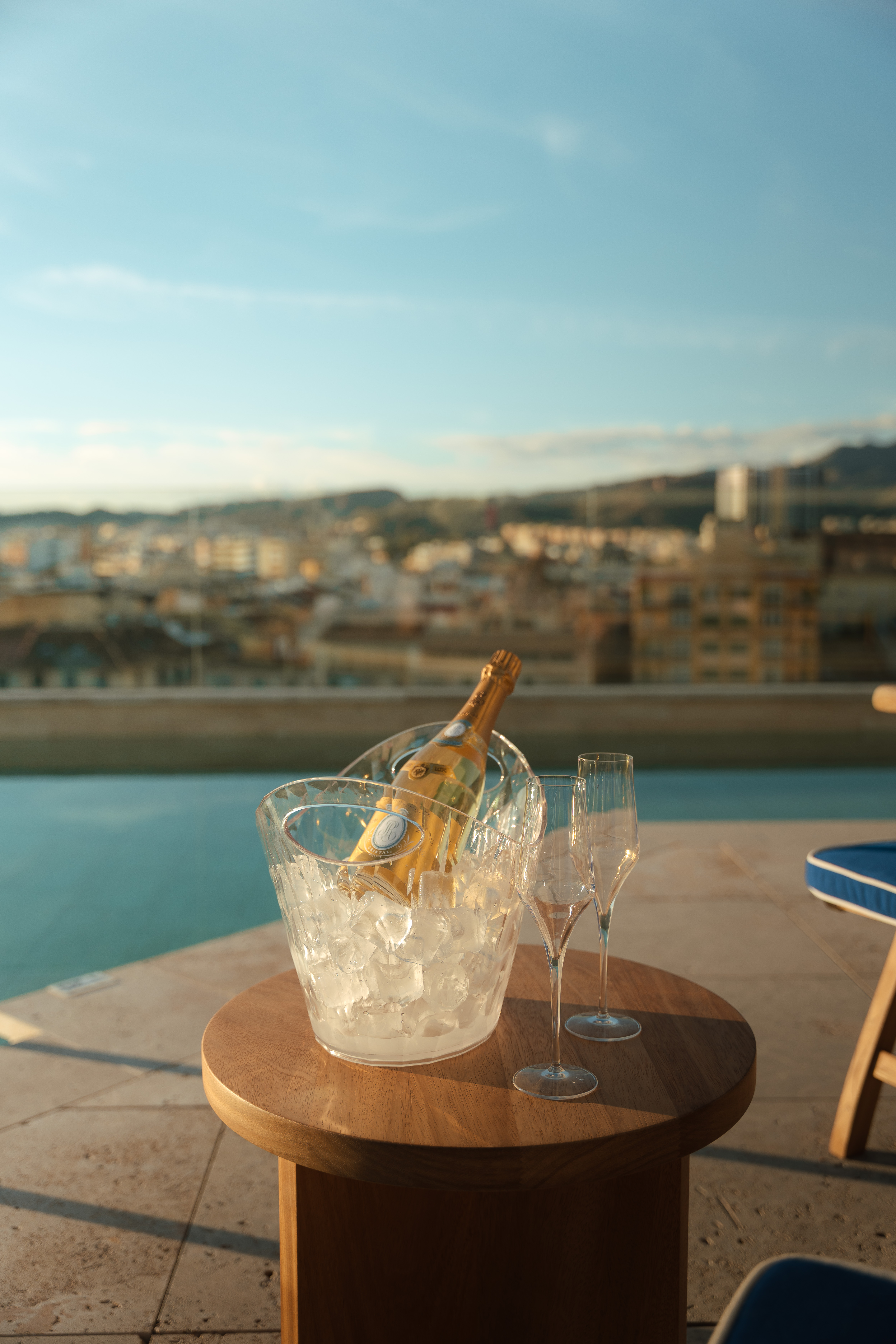 a bottle in a bucket of ice and two glasses on a table