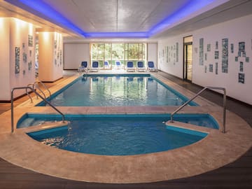 a indoor pool with a large tub and chairs