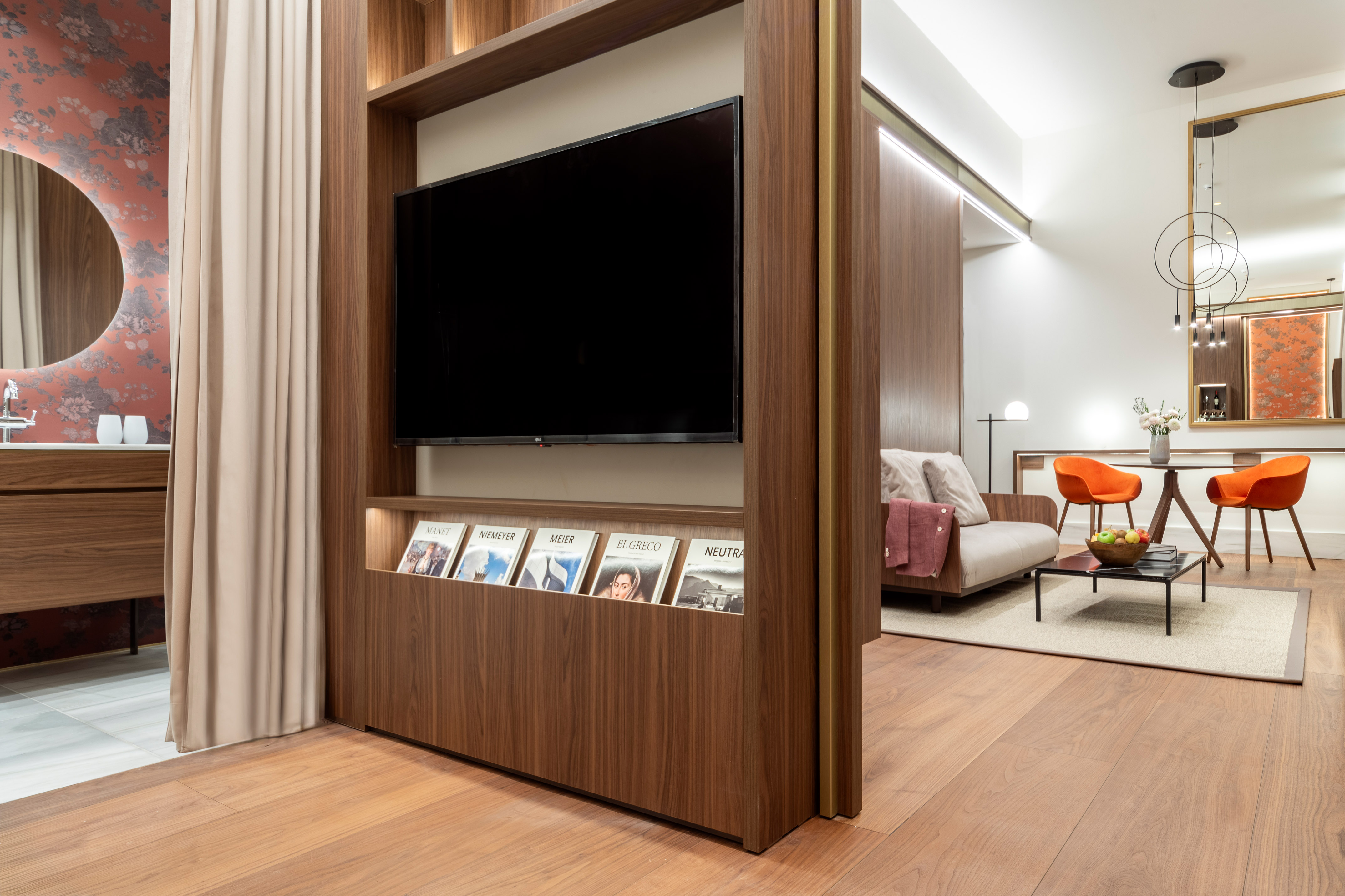 Modern hotel suite: wooden TV partition, living area, and elegant bathroom.