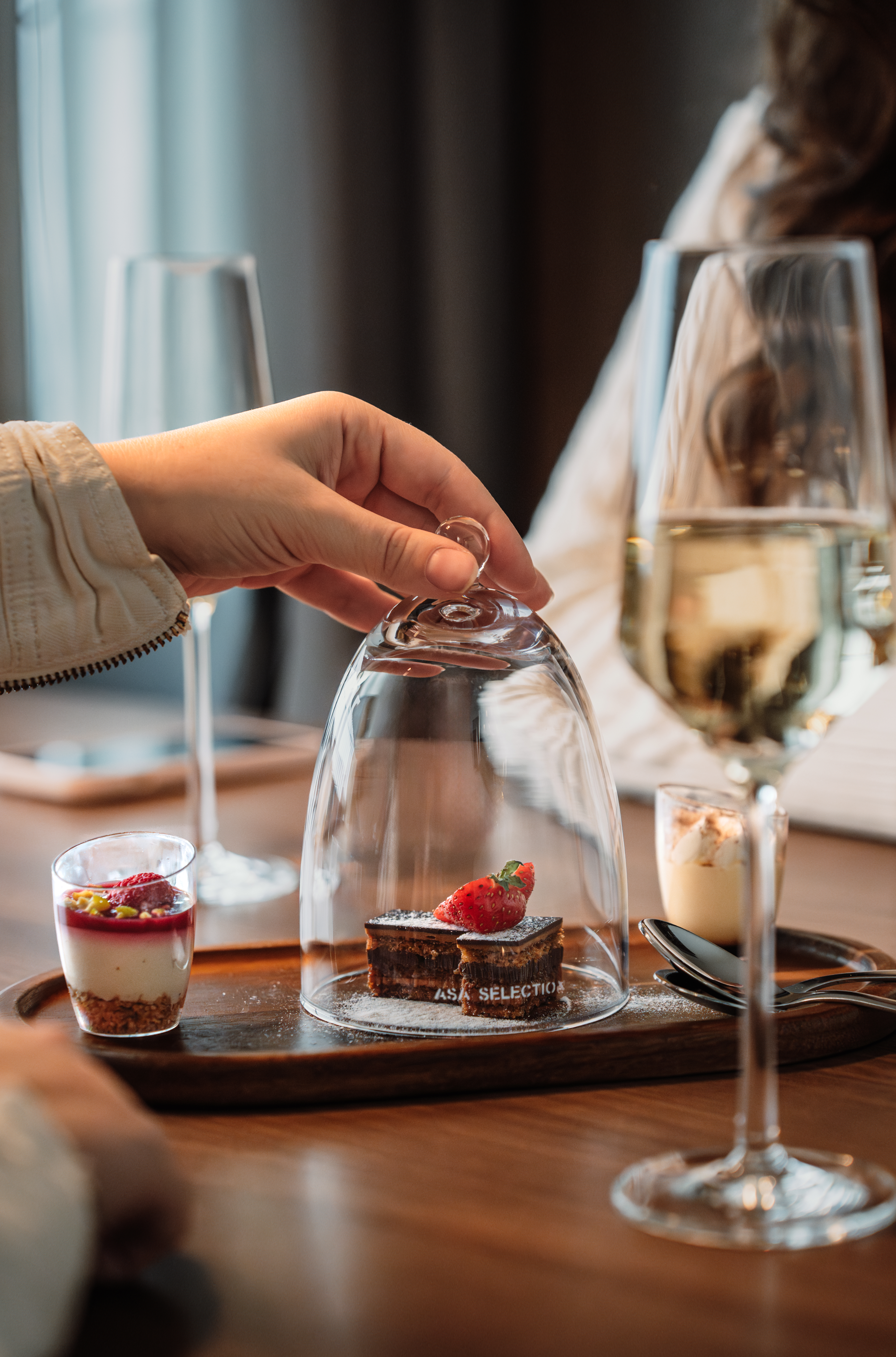 a hand holding a glass cover with a dessert inside