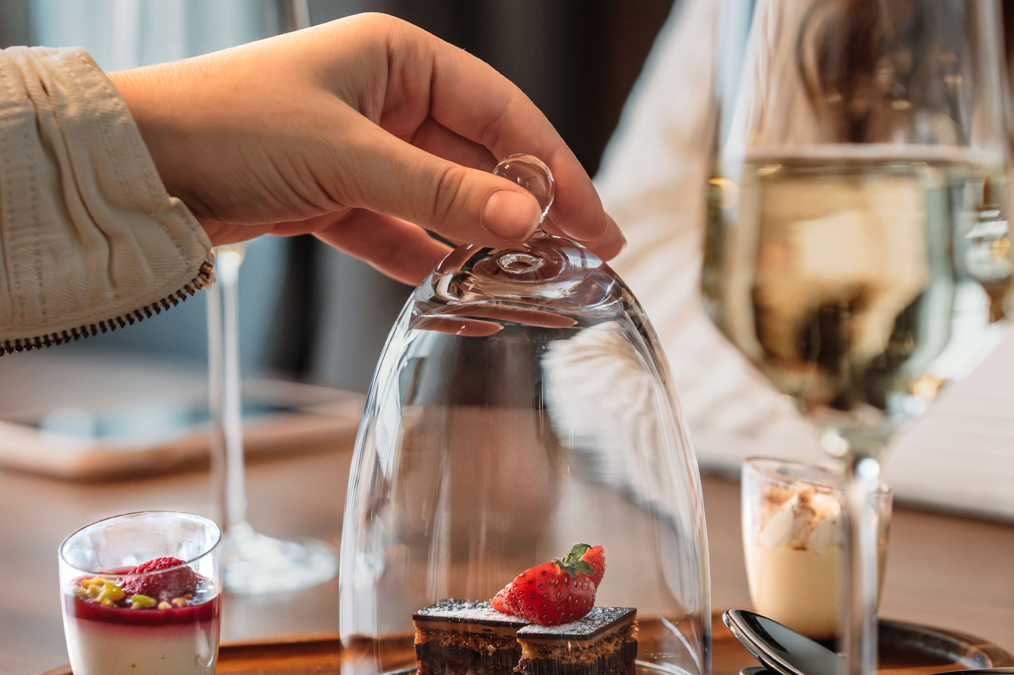 a hand holding a glass cover with a dessert inside