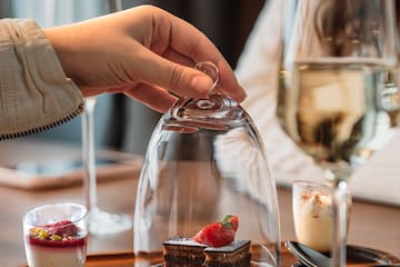a hand holding a glass cover with a dessert inside