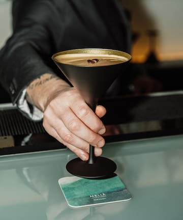a hand holding a glass with liquid in it