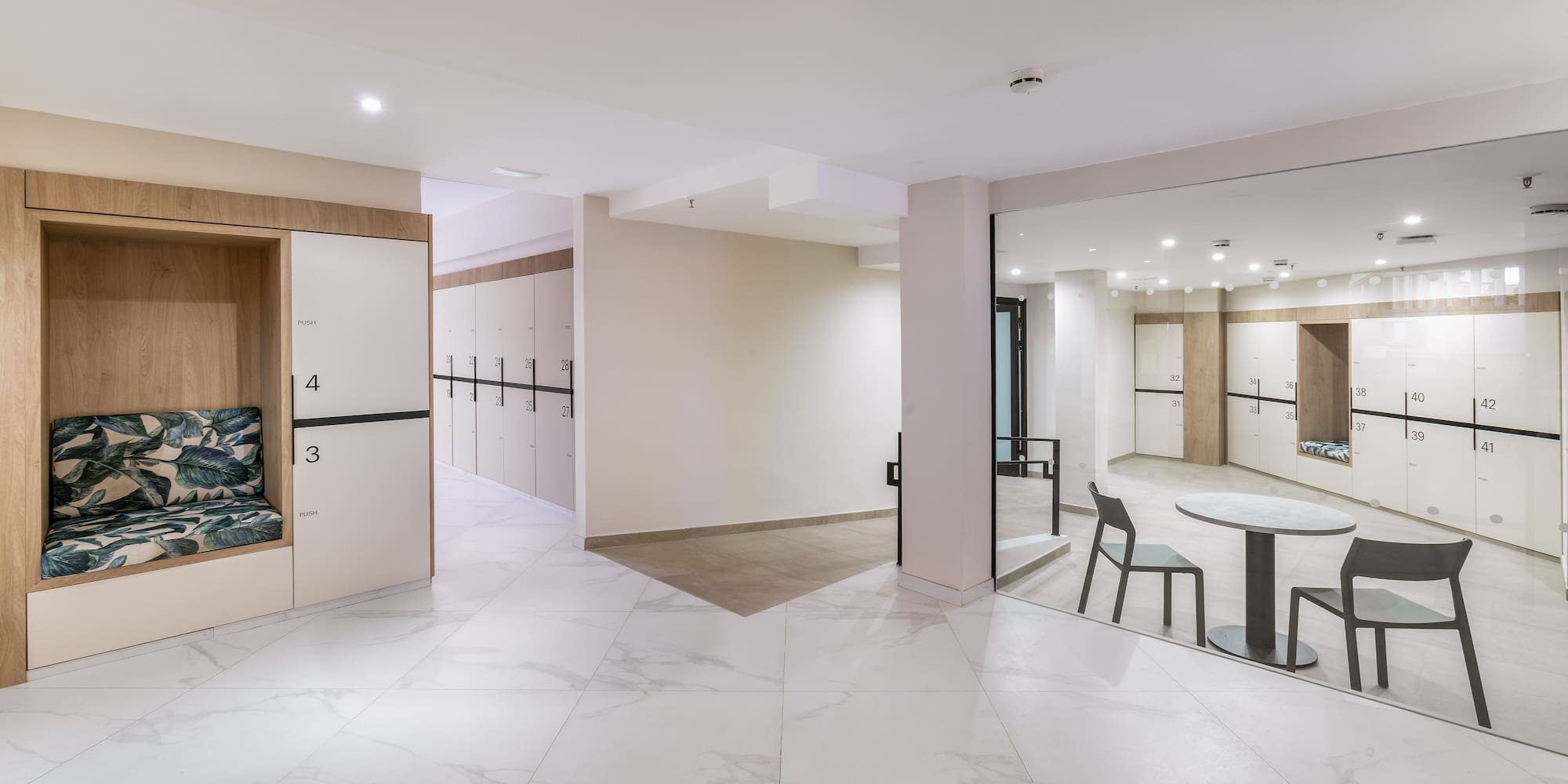 Modern locker room with white lockers, marble floor, and seating booths.