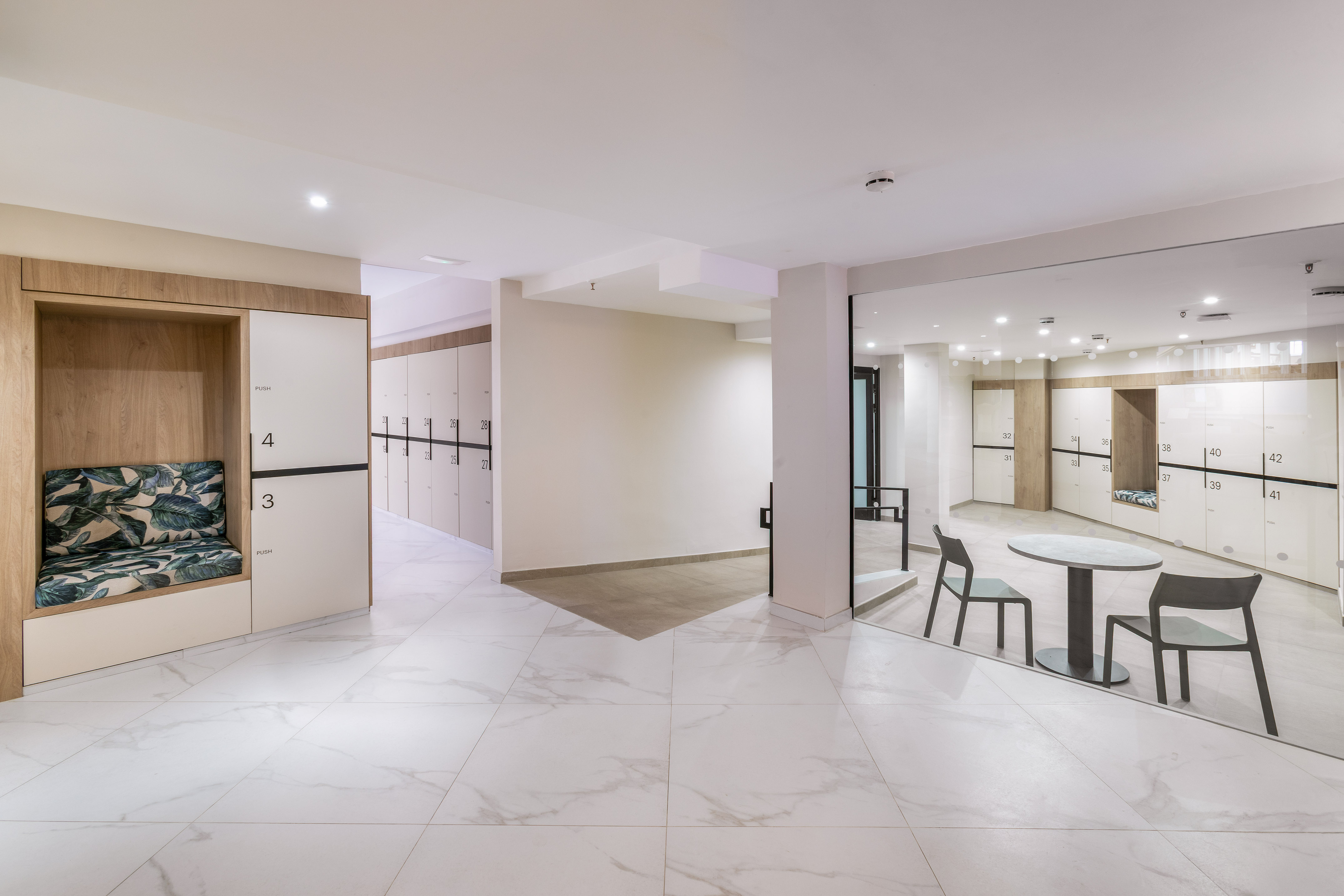 Modern locker room with white lockers, marble floor, and seating booths.