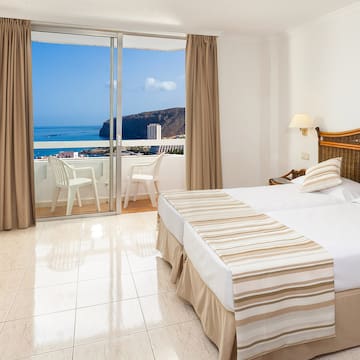 a bedroom with a view of the ocean and a beach