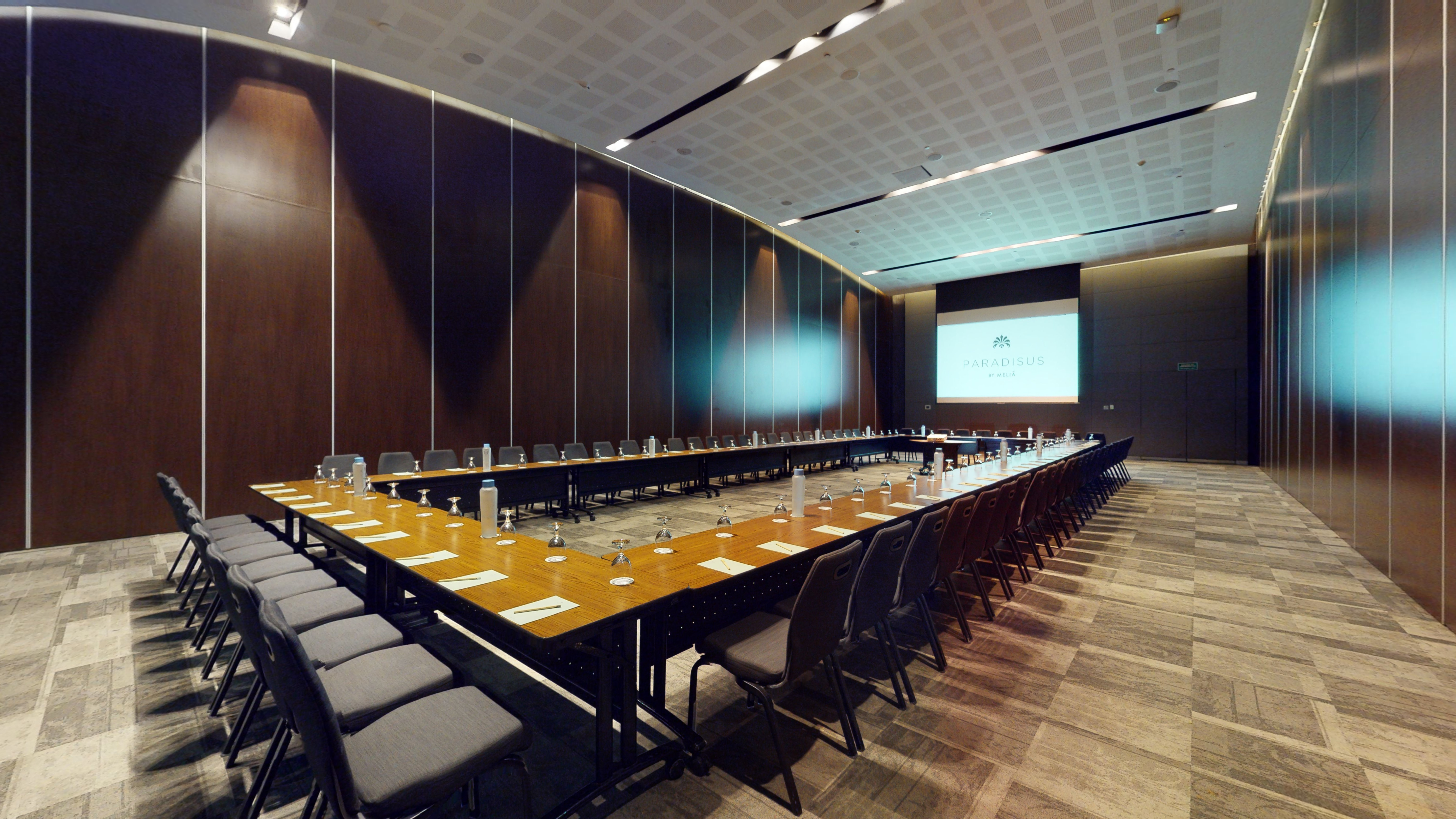 Modern U-shaped conference room setup with Paradisus by Meliá screen.