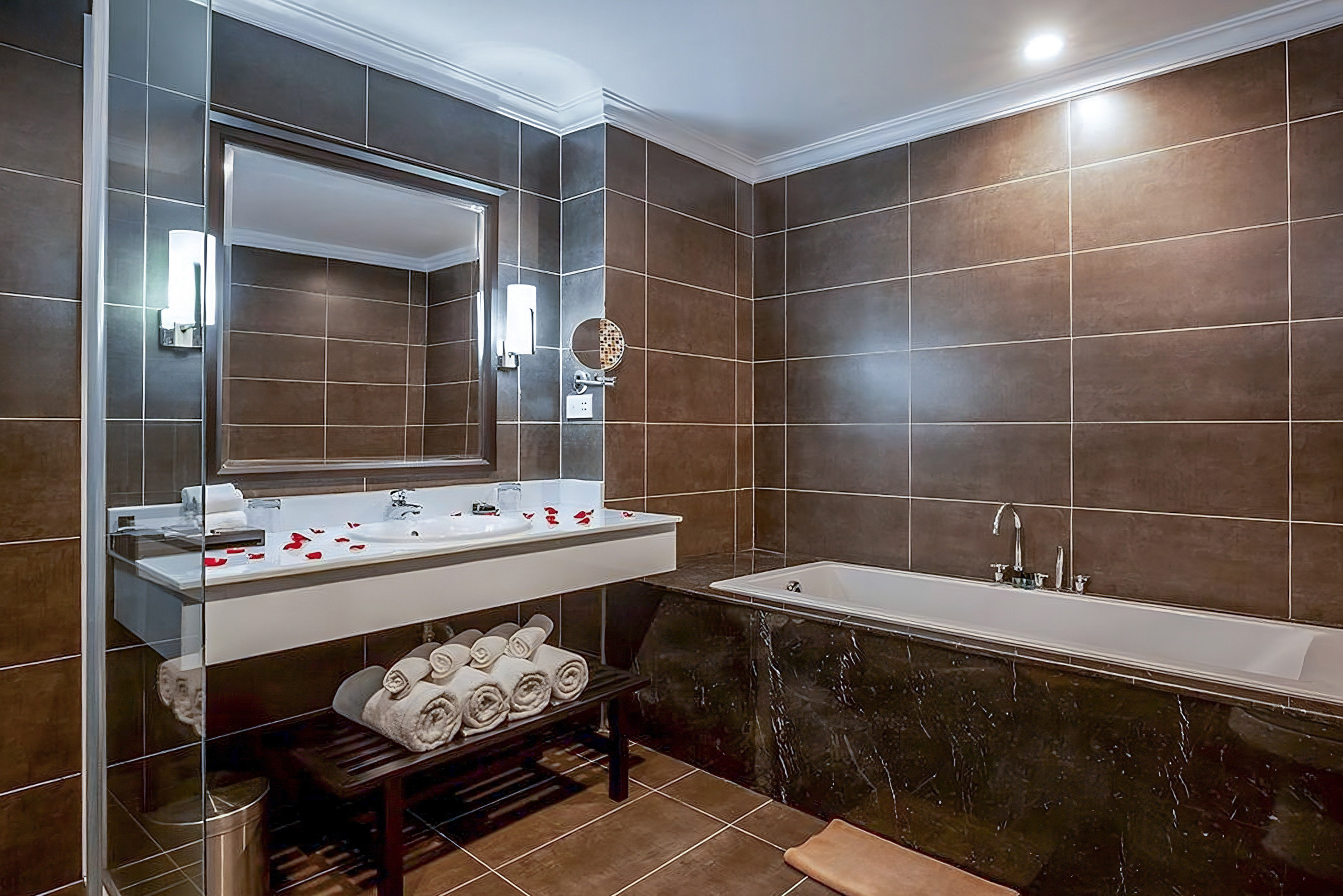 Spa-like bathroom with brown tiles, double vanity, mirror, bathtub, and rose petals. - Family Room - Hotel Sapa Square Affiliated by Meliá, Sapa