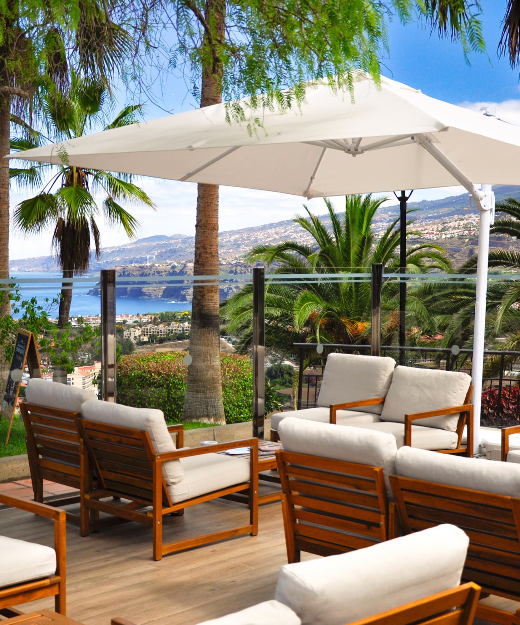 a patio with white chairs and a white umbrella