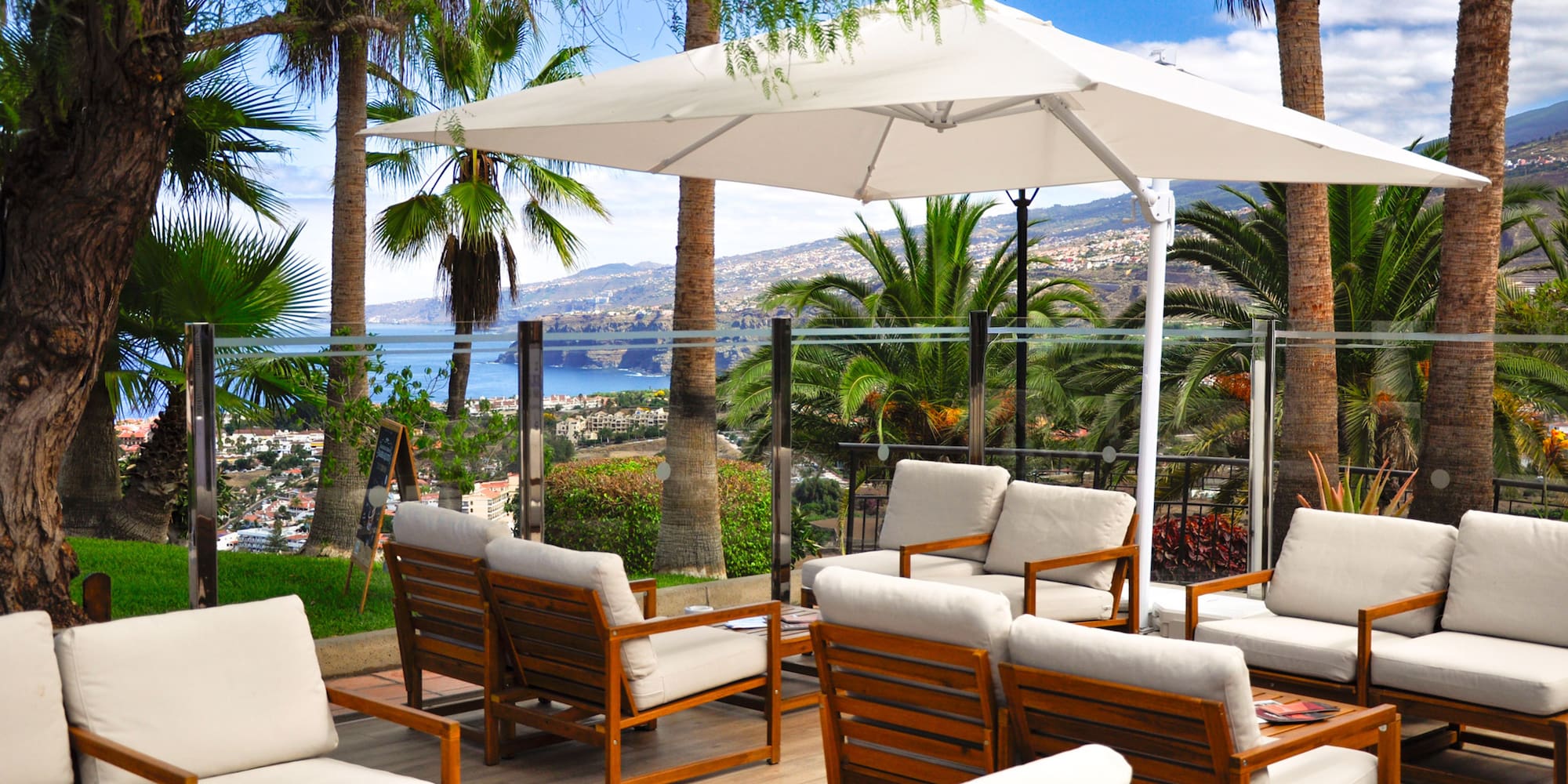 a patio with white chairs and a white umbrella