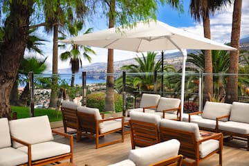 a patio with white chairs and a white umbrella