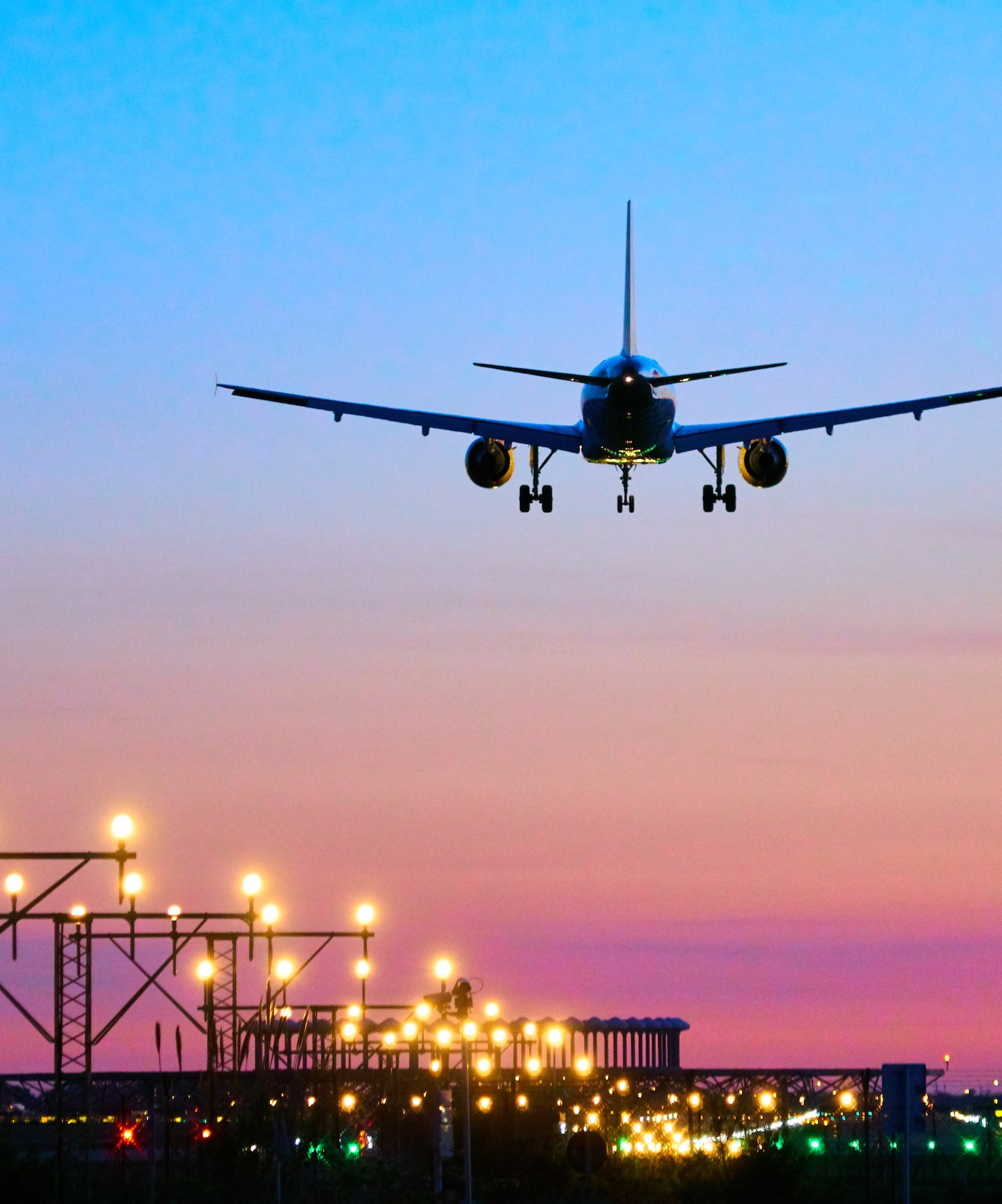 Avión comercial aterrizando sobre aeropuerto iluminado al anochecer.