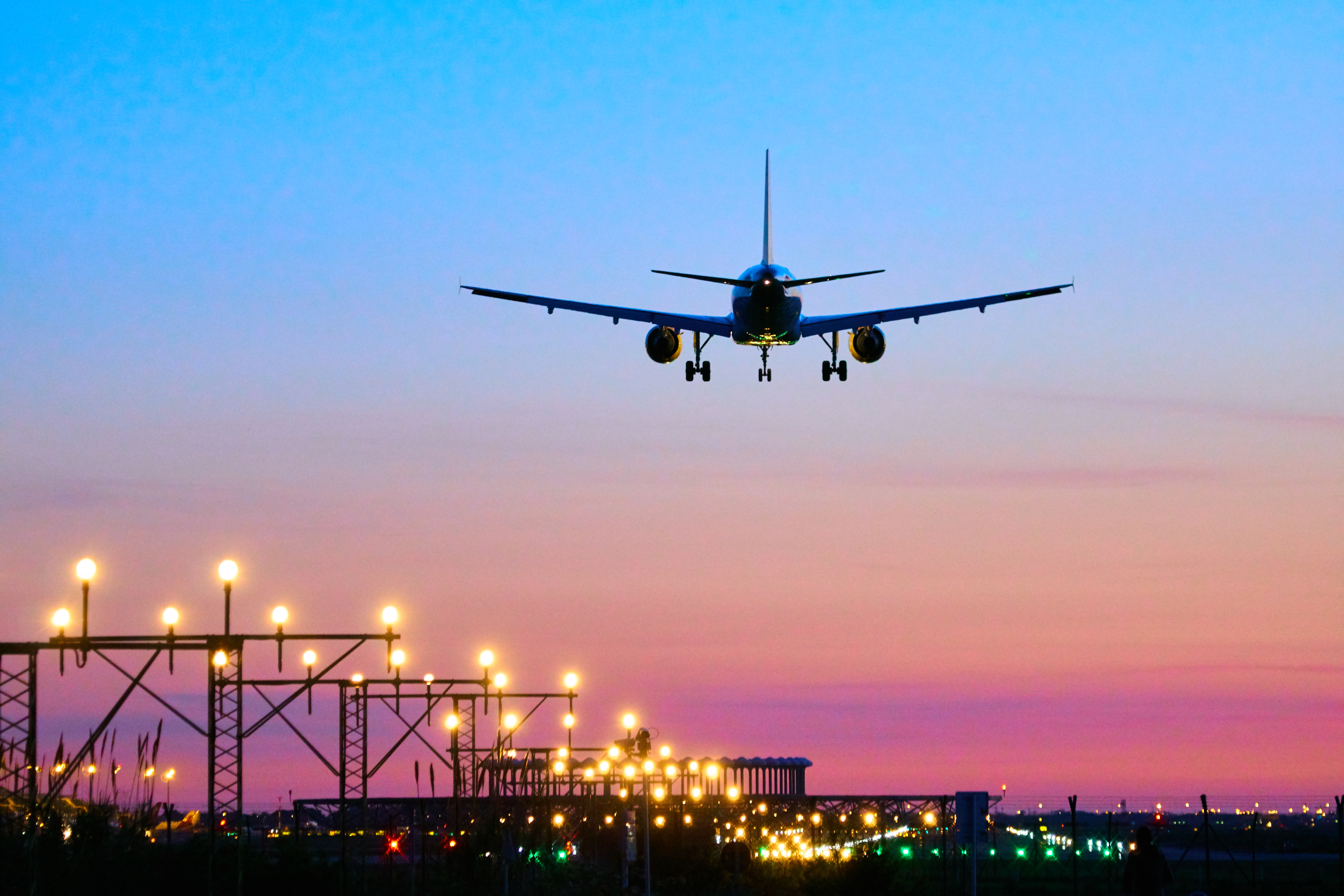 Avión comercial aterrizando sobre aeropuerto iluminado al anochecer.
