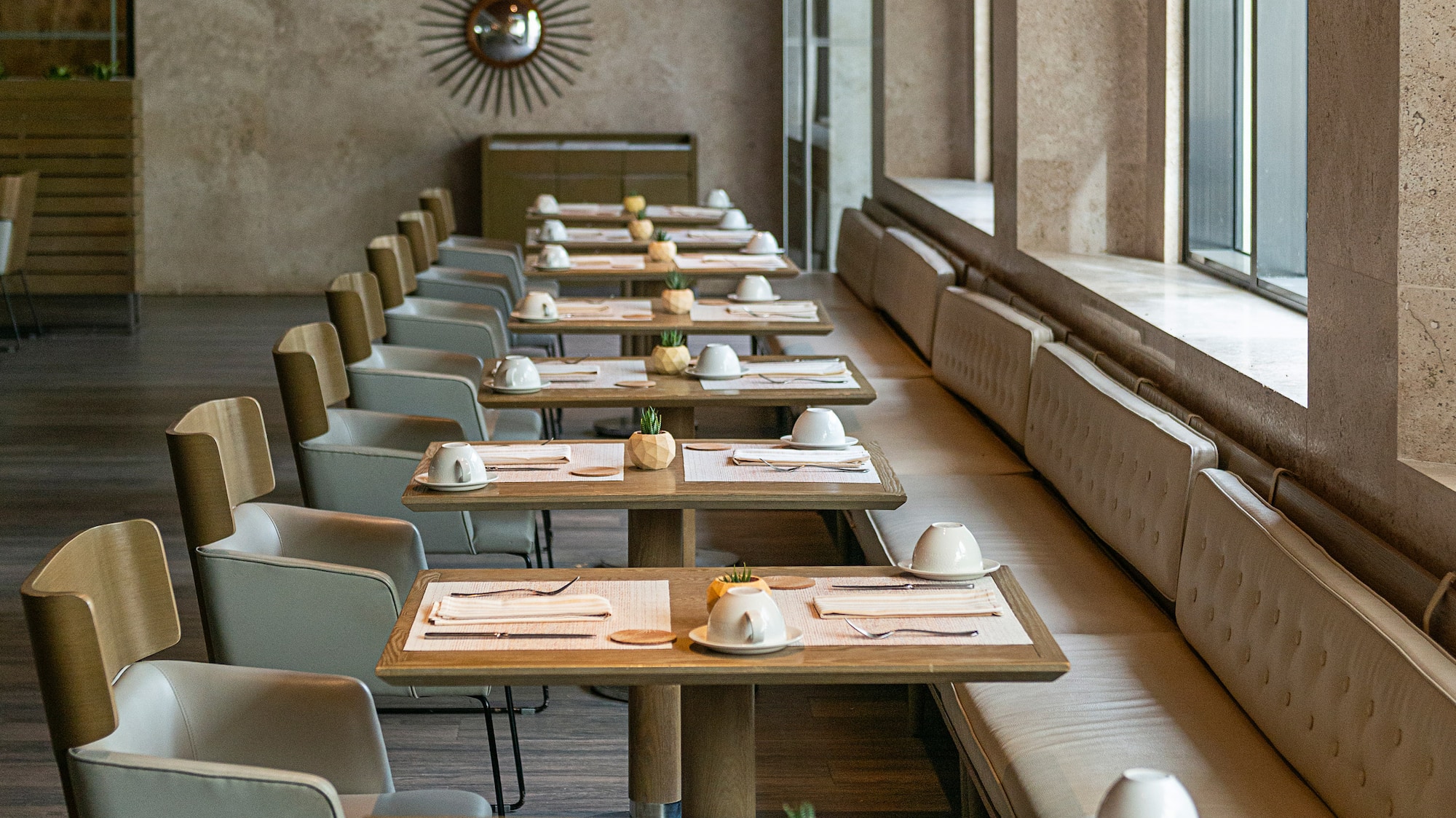 a long table with white chairs and plates on it
