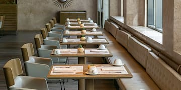 a long table with white chairs and plates on it