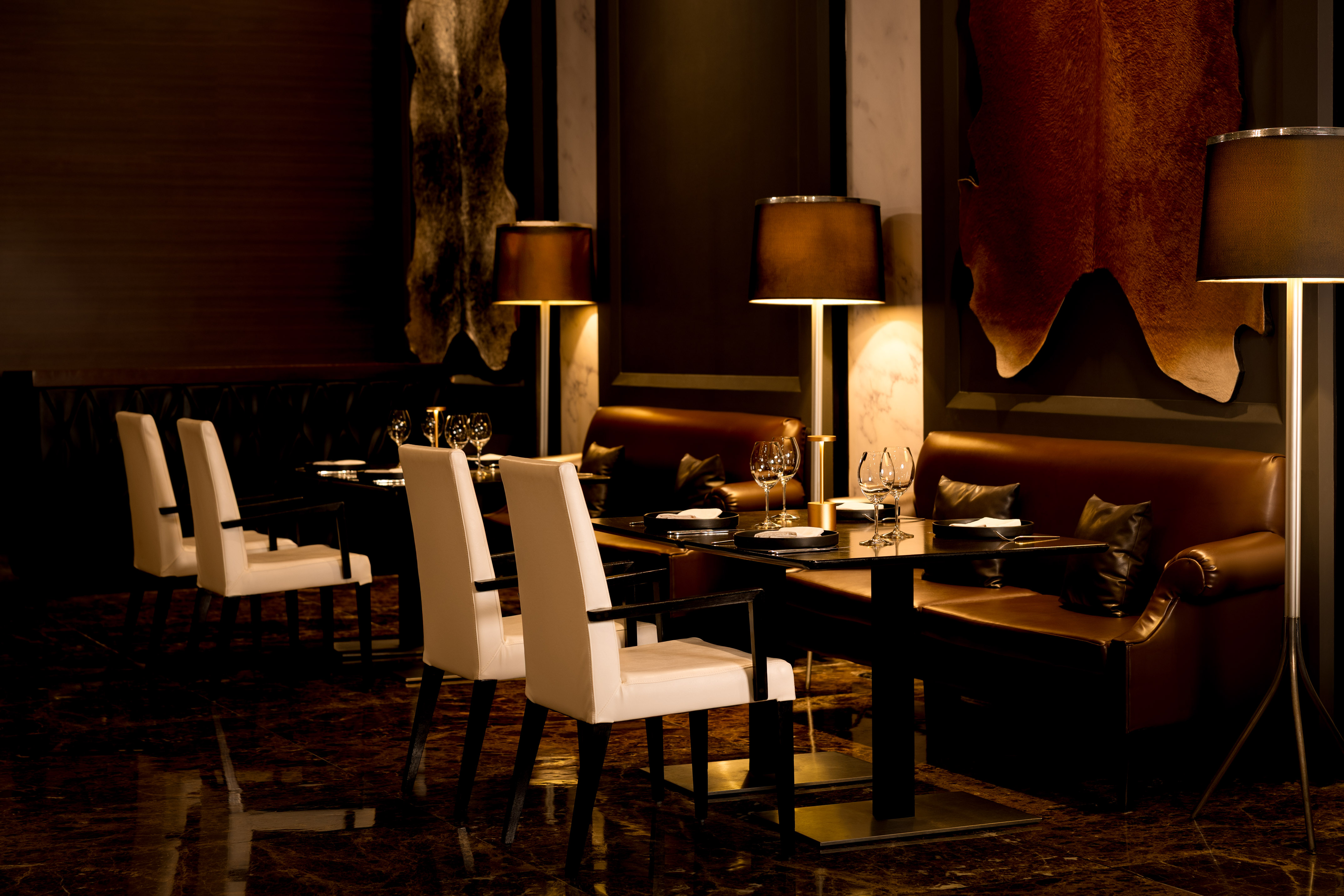Luxury restaurant interior with white chairs, leather seating, and hide decor.