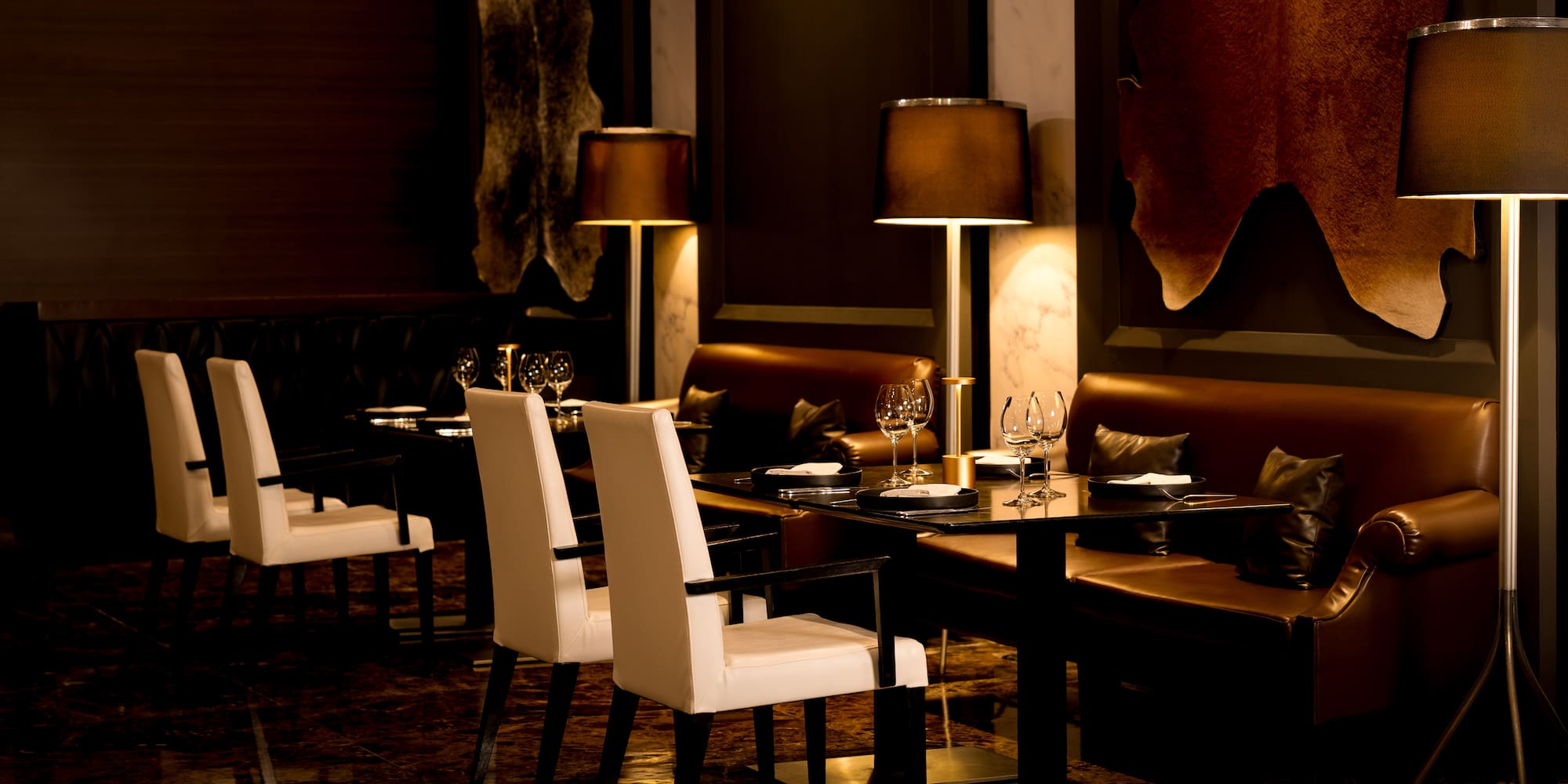 Luxury restaurant interior with white chairs, leather seating, and hide decor.