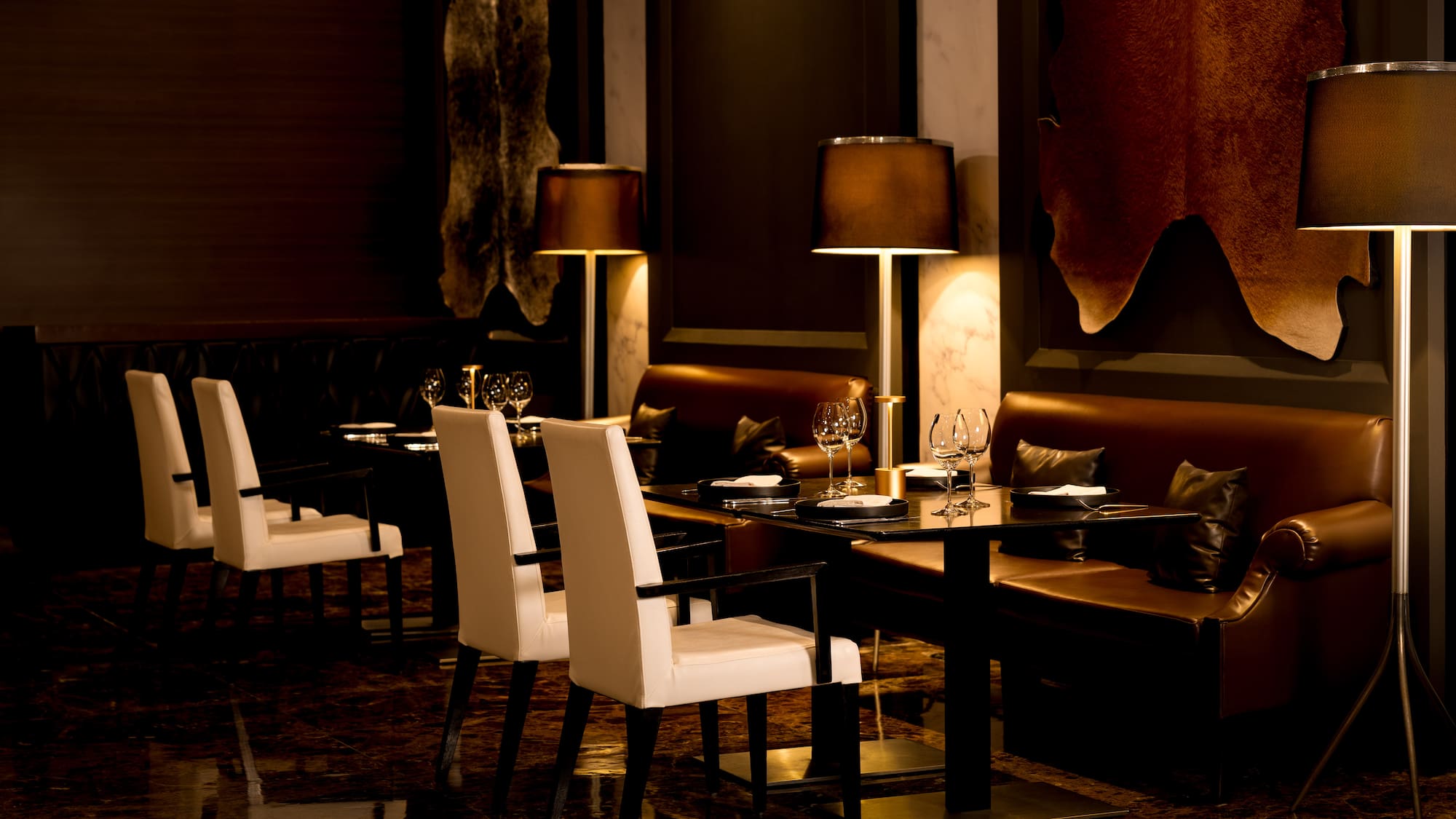 Luxury restaurant interior with white chairs, leather seating, and hide decor.