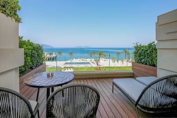 a deck with chairs and a table overlooking the ocean