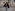 Woman in red faux fur coat, jeans, coffee, sunglasses, walking city street.