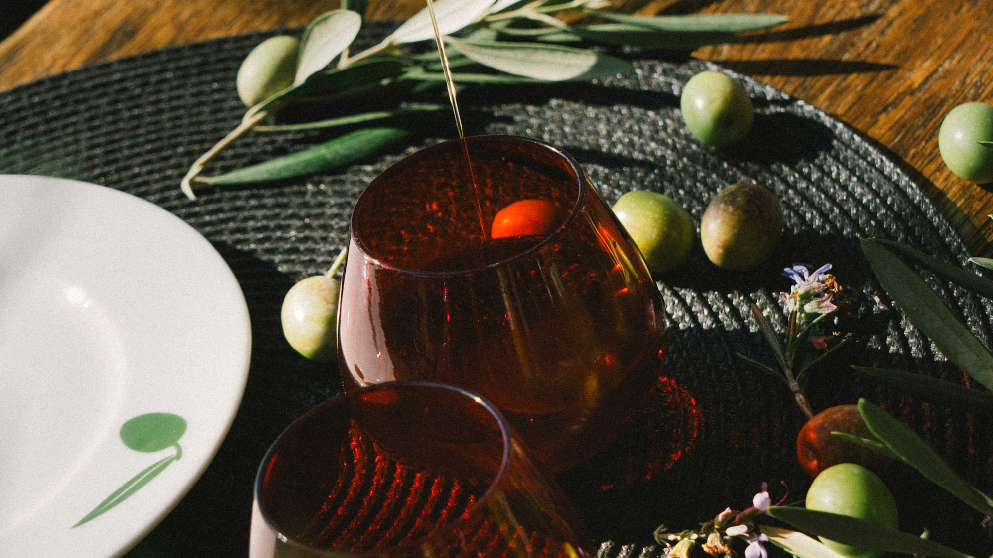 a bottle pouring olive oil into two glasses