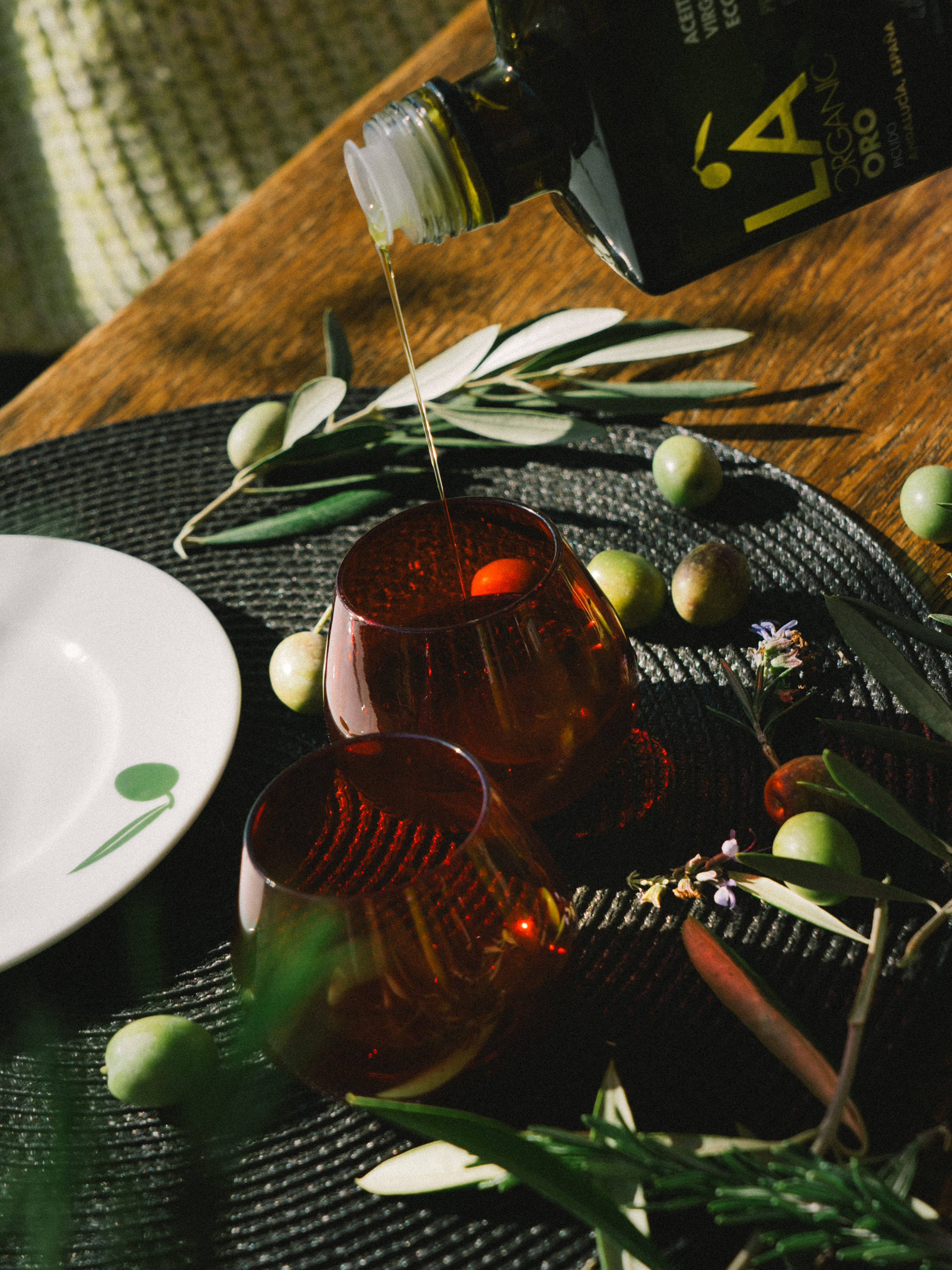 a bottle pouring olive oil into two glasses