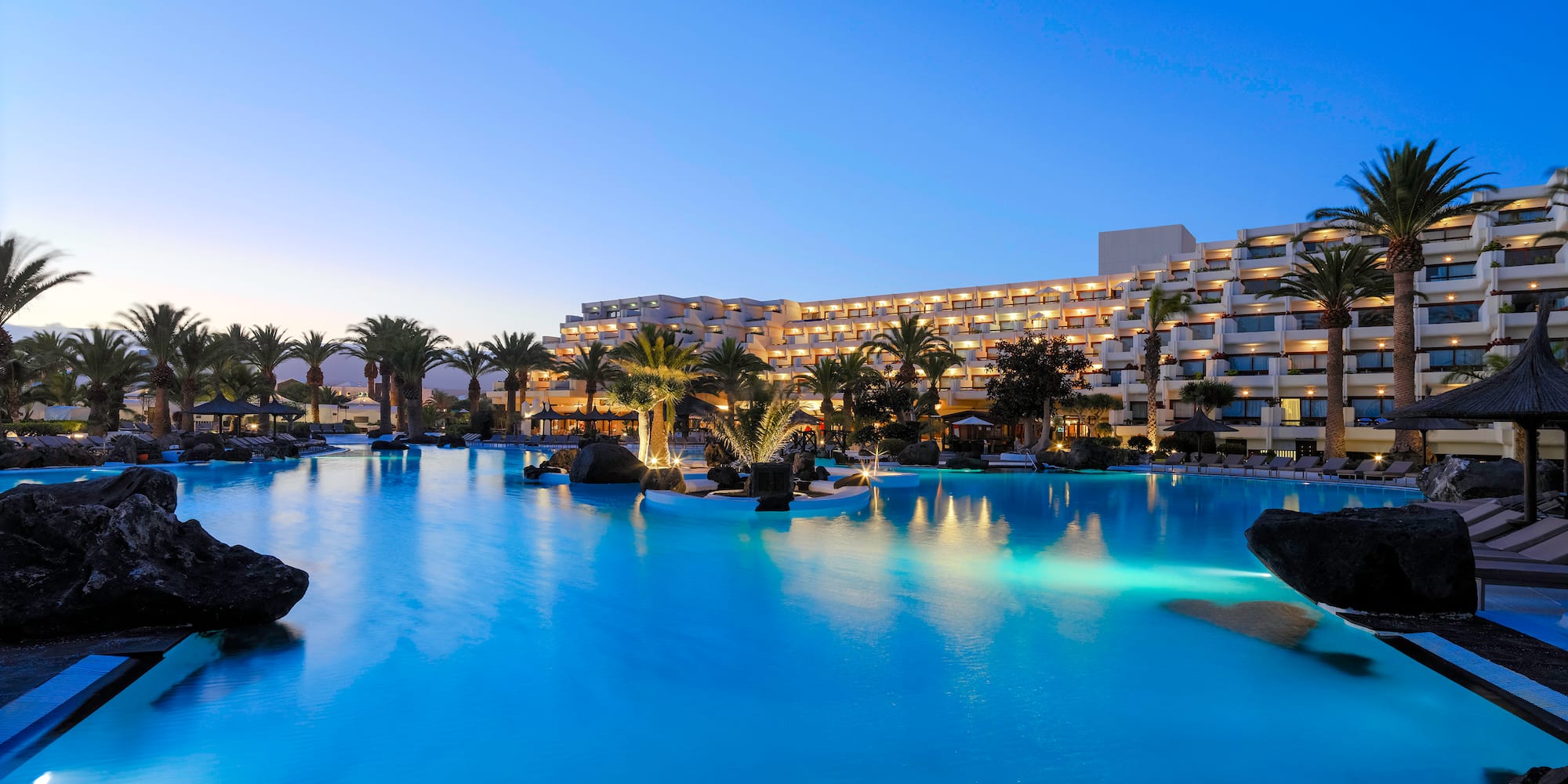 a pool with palm trees and a building in the background