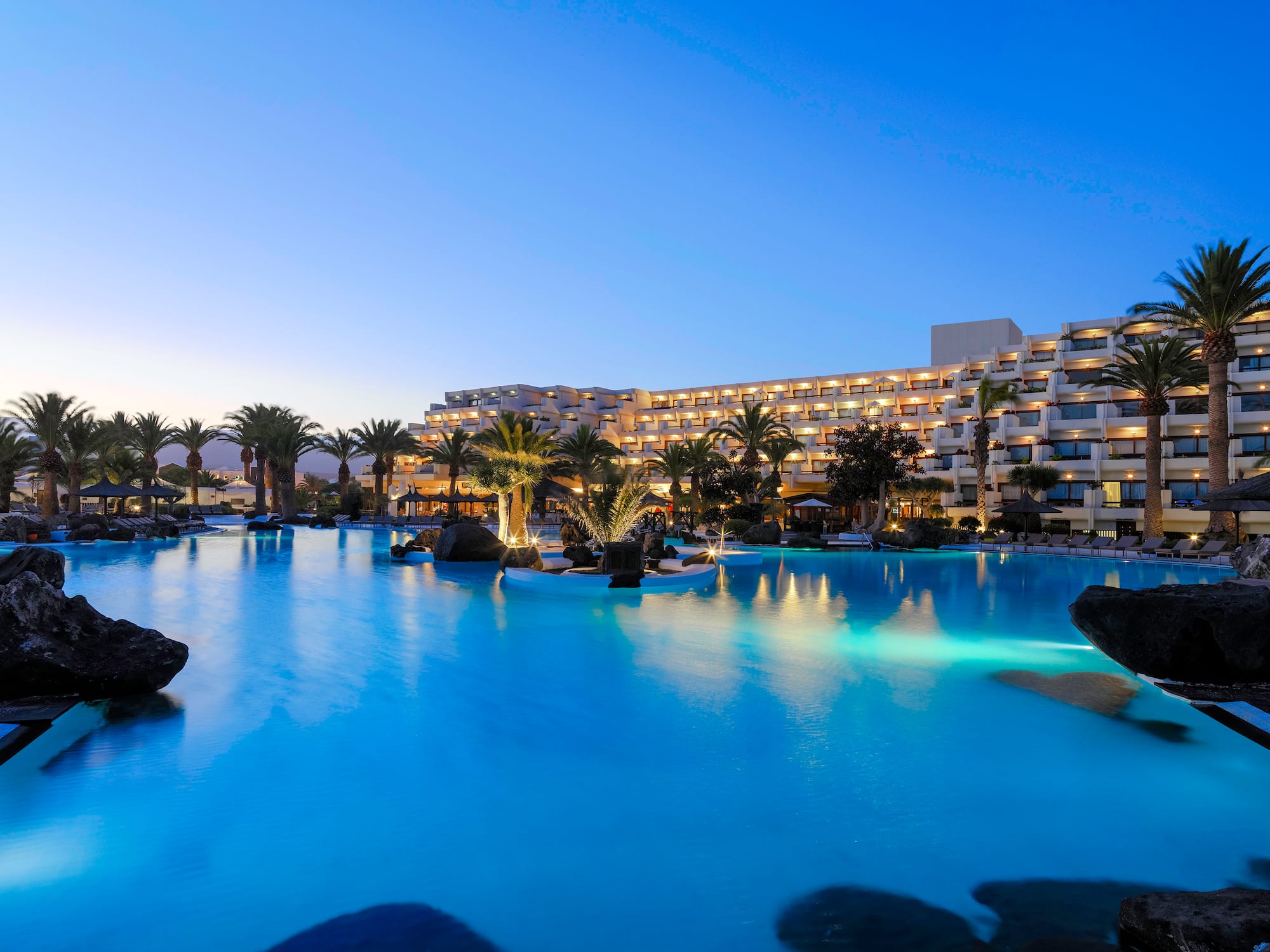 a pool with palm trees and a building in the background