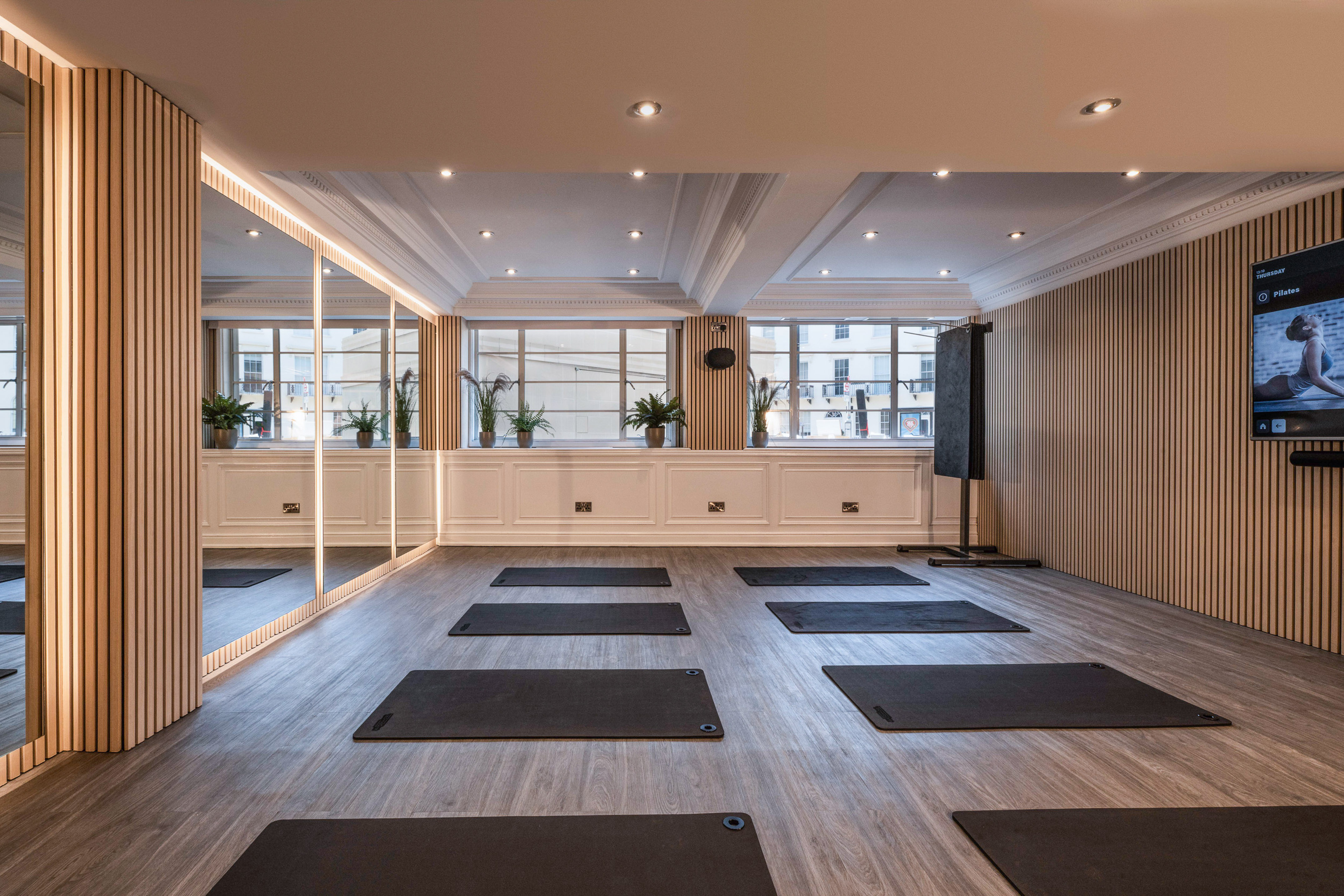 Modern pilates studio featuring wood-slat walls, mirrors, and exercise mats.