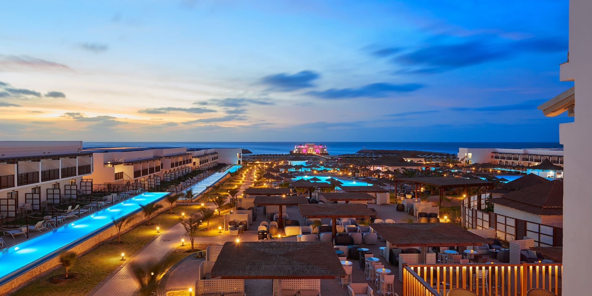 a rooftops of a resort with a pool and a body of water