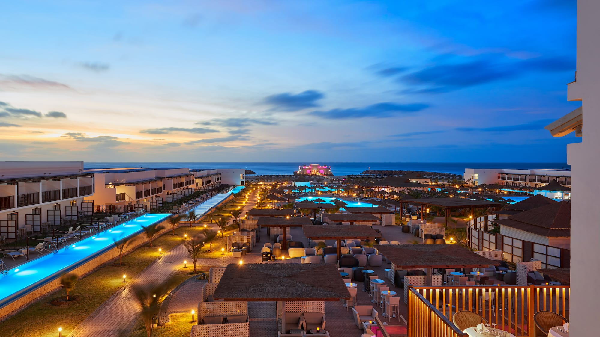 a rooftops of a resort with a pool and a body of water
