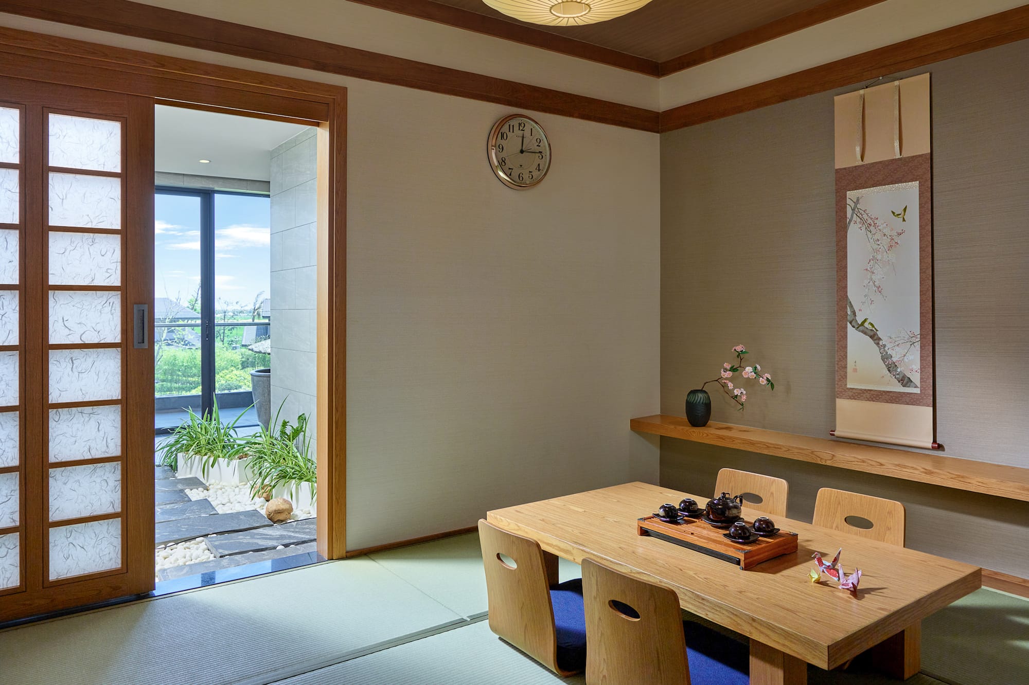 Japanese tatami room interior with wooden tea table, shoji door, and scroll art.