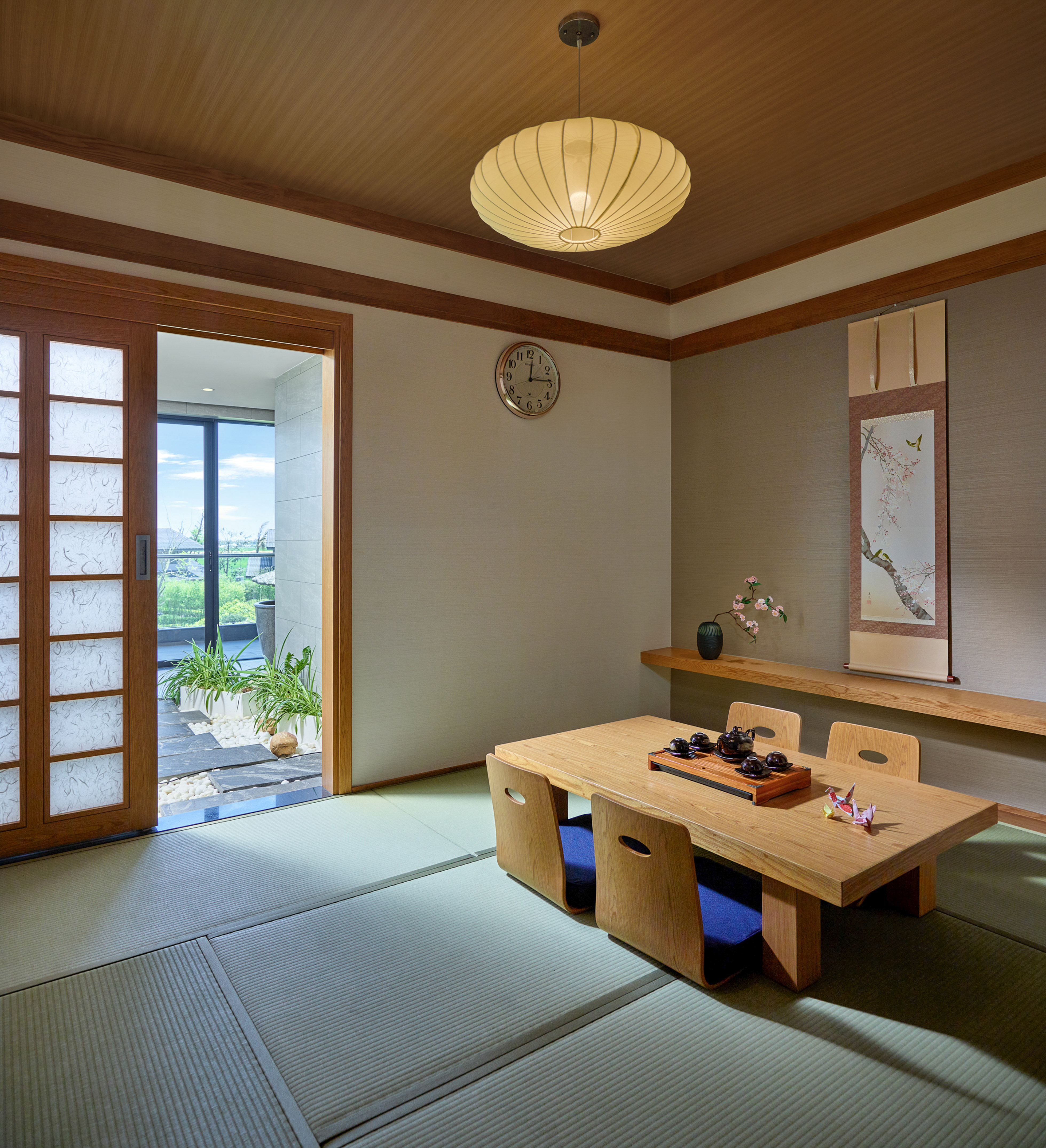 Japanese tatami room interior with wooden tea table, shoji door, and scroll art.